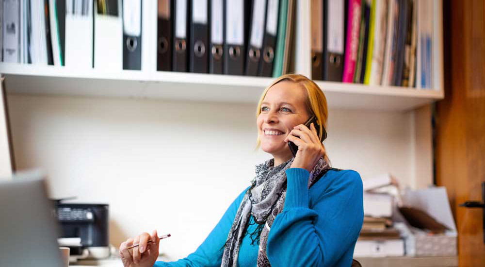 Woman sitting at a desk talking on a mobile phone